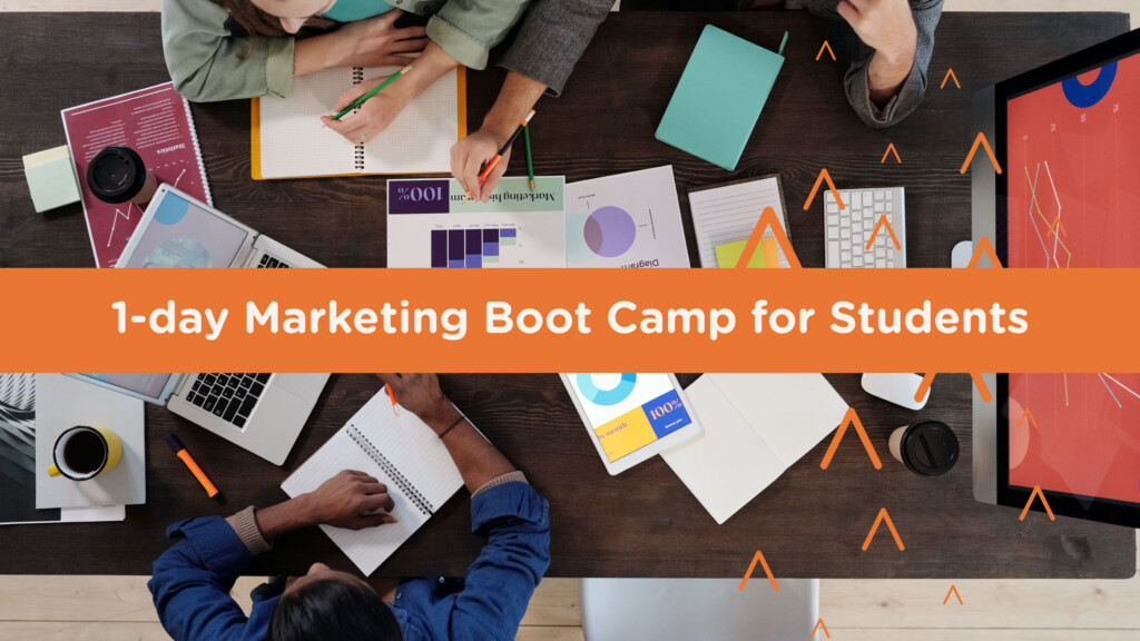 overhead image of a table filled with laptops and notebooks, showing the hands of young people working