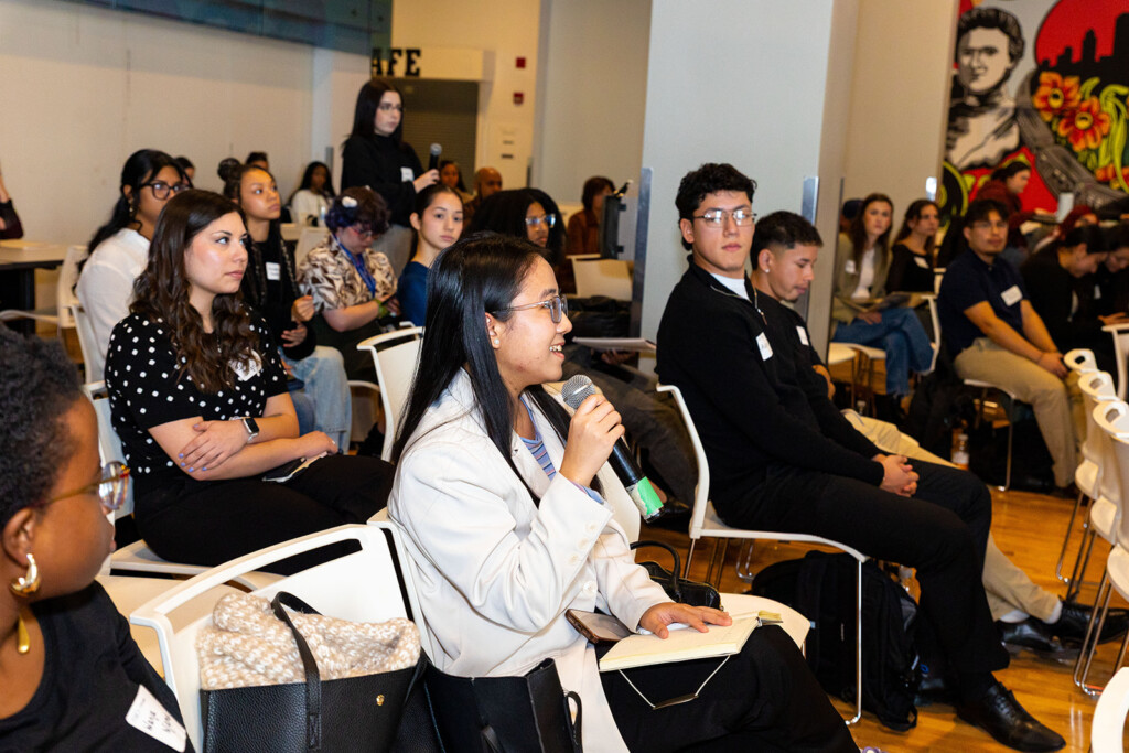 Photo of a student in the audience asking a question of the speaker at 2025 Marketing Boot Camp. Other audience members are looking on with interest